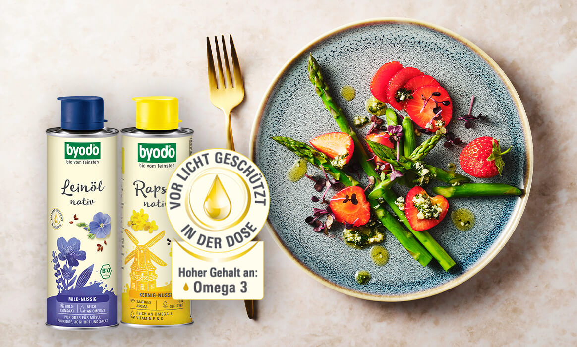 Byodo Leinöl und Rapsöl nativ im Vordergrund, Salatteller mit Spargel und Erdbeeren